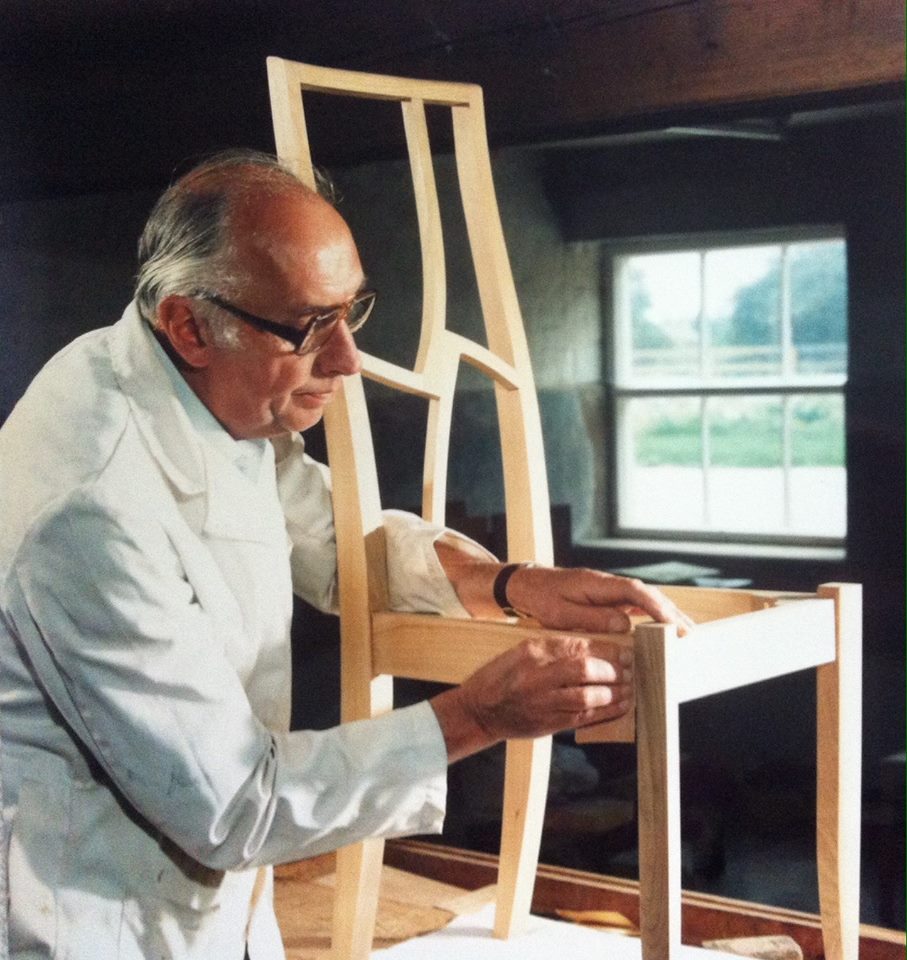 A crafstman sin a workshop sanding a dining chair