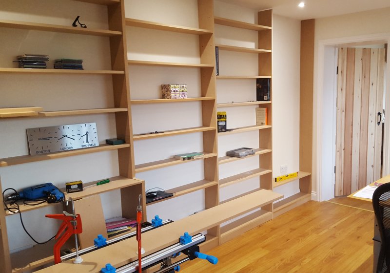 Built in shelving under construction along one wall of a room