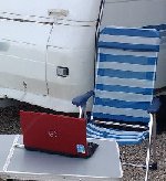 close up of an outdoor chair anad a laptop outside a caravan