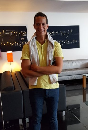A man stands, smiling, in front of setees in a hotel reception area