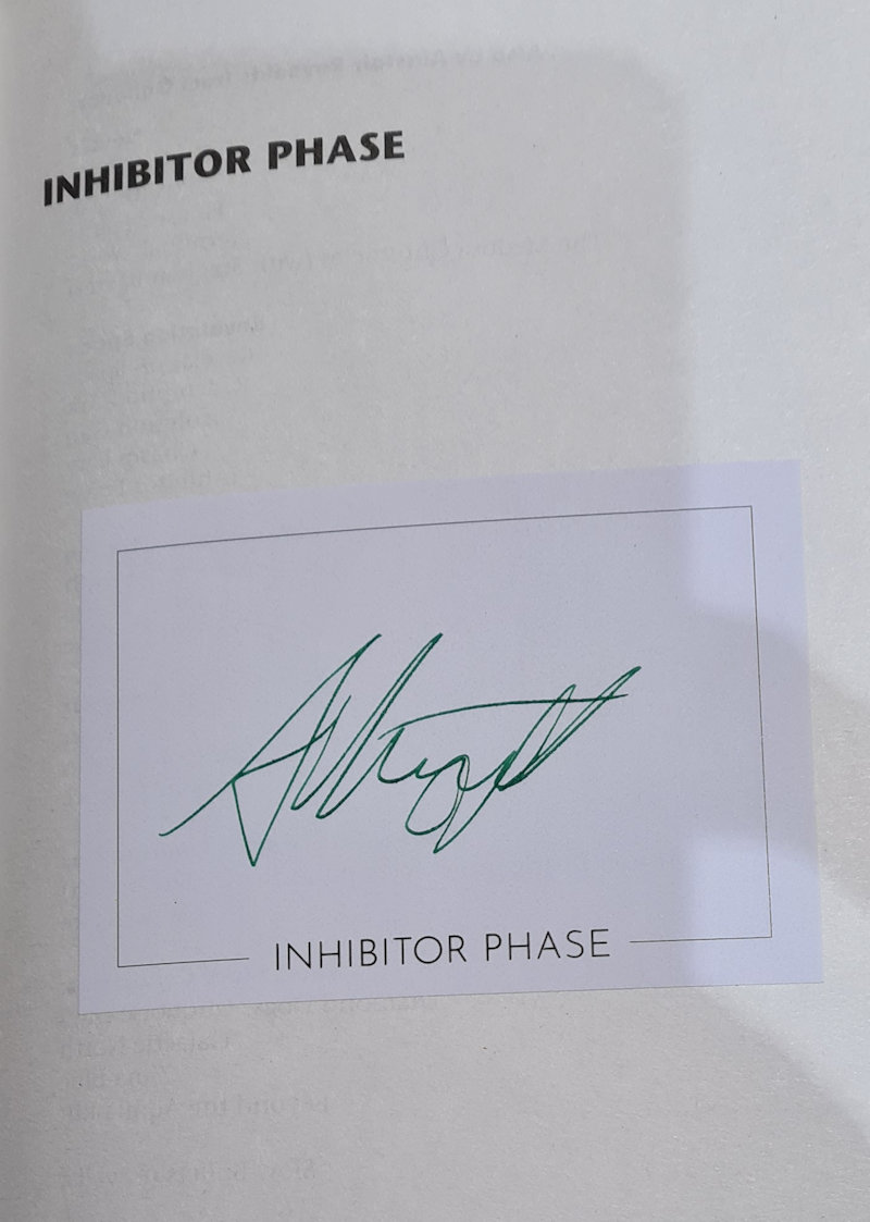 A page of a book. The title, Inhibitor Phase, is at the top. A signature is on a label, pasted onto the page