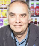 A close-cropped picture of Phil Archer in front of a supermarket soft drinks fridge