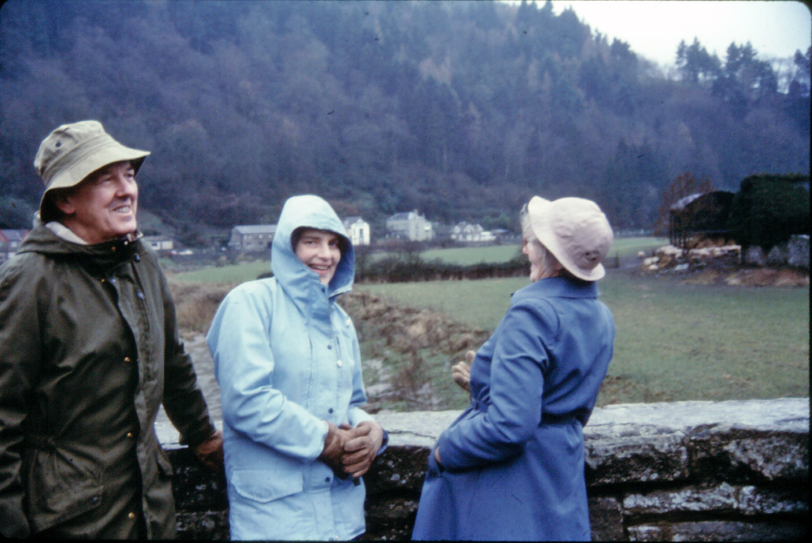 A group of 3 middle-aged people on a wet day in the French countryside